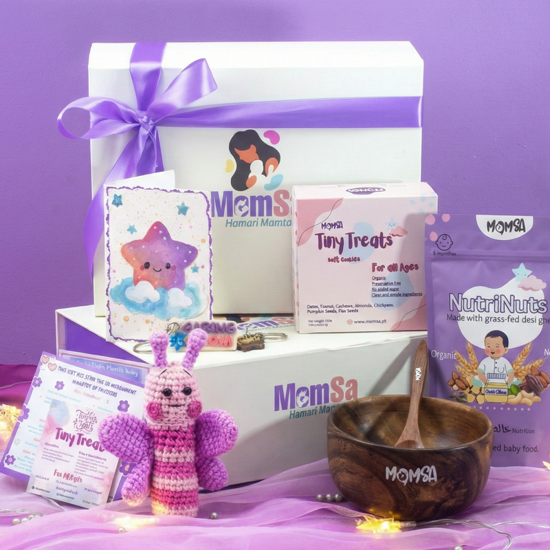 Gift box with organic baby products including a wooden bowl , toys, and packaging on a purple background